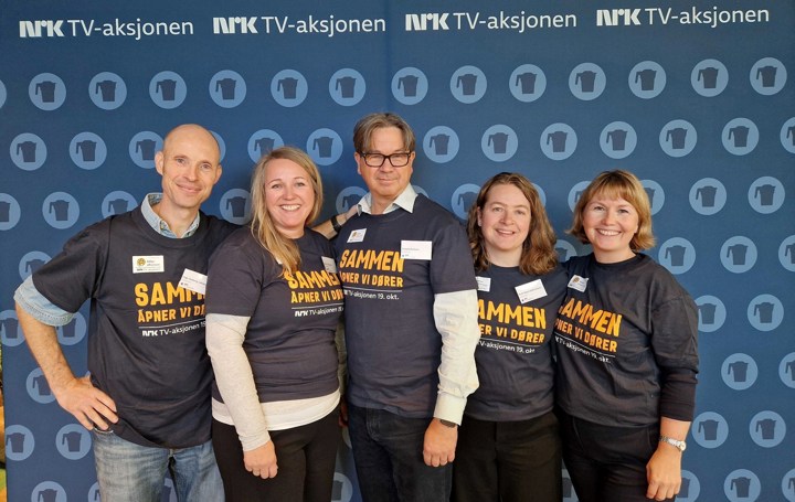 Fem mennesker står med t-skjorter med skriften Sammen åpner vi dører. 