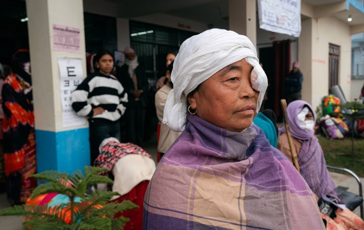 Kvinne i Nepal sitter med lapp foran øyet ved øyeklinikk. 