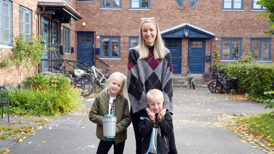 En mor og to barn står med bøsse i et nabolag.