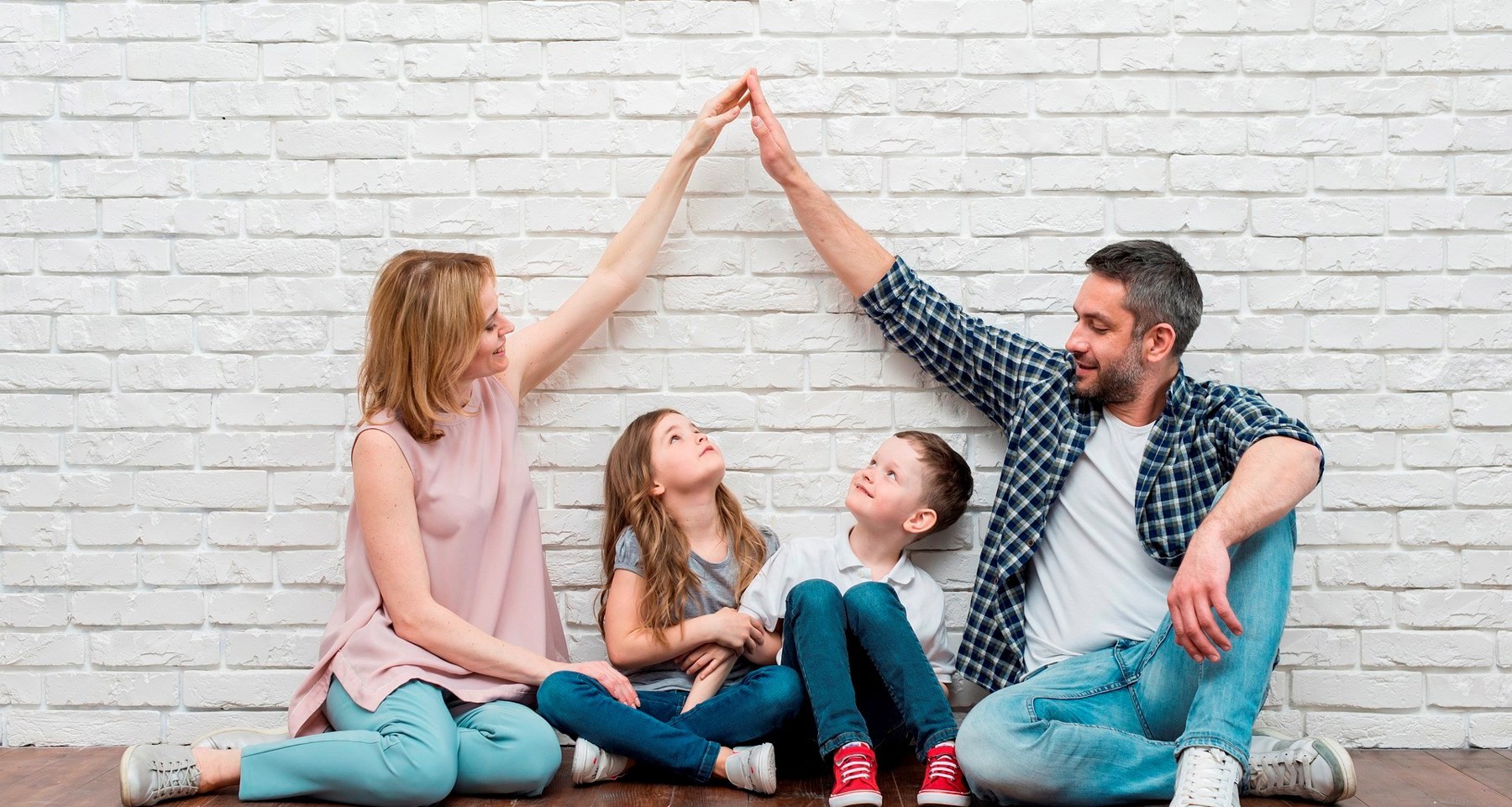 Familie Sitter Med Armer Som Tak Stock Photo